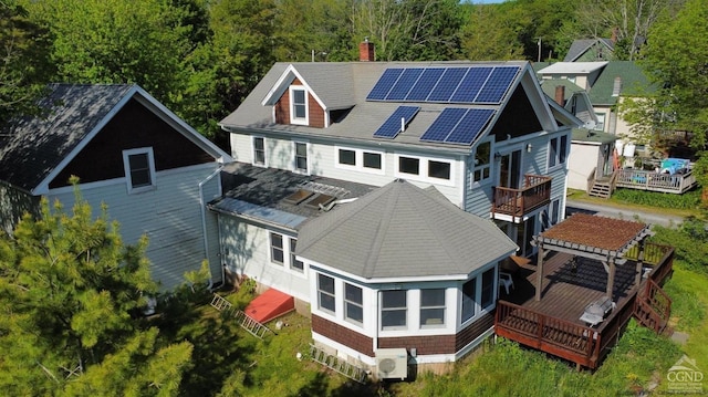 rear view of house featuring solar panels and a wooden deck