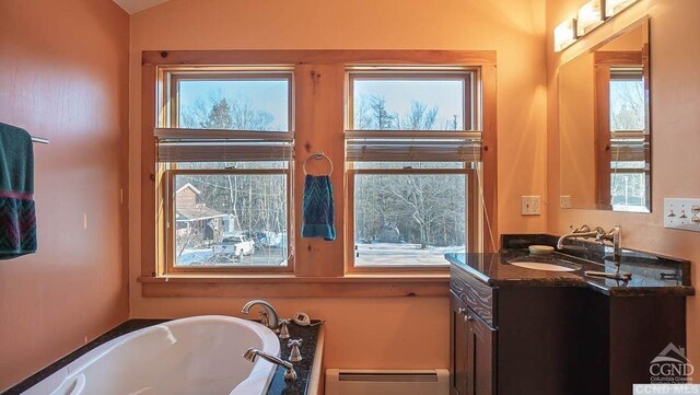 bathroom with a bathtub, vanity, a baseboard radiator, and a wealth of natural light