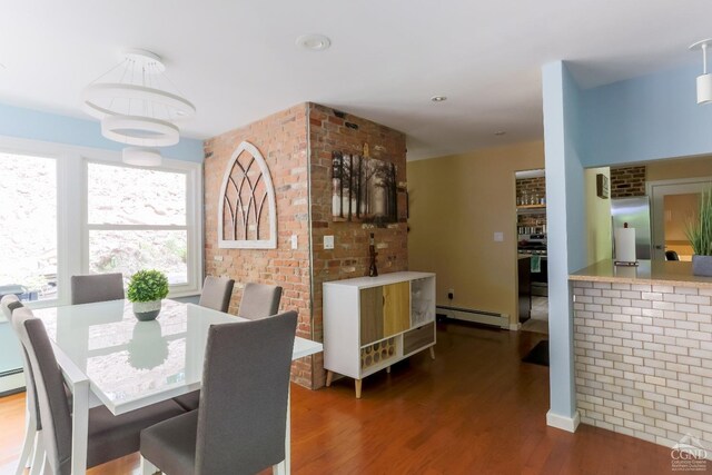 dining area with dark hardwood / wood-style flooring, brick wall, and a baseboard radiator