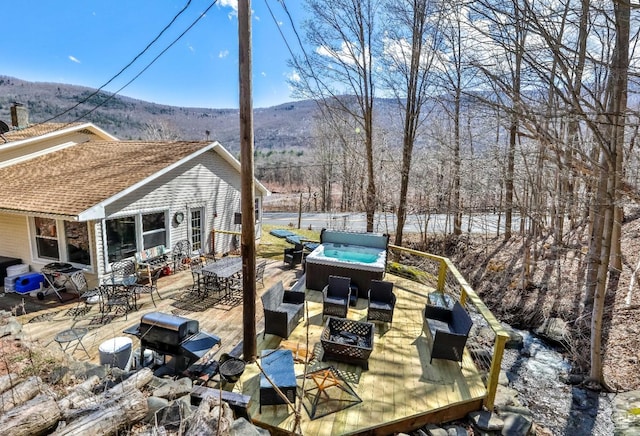 deck with a mountain view, outdoor lounge area, and a hot tub