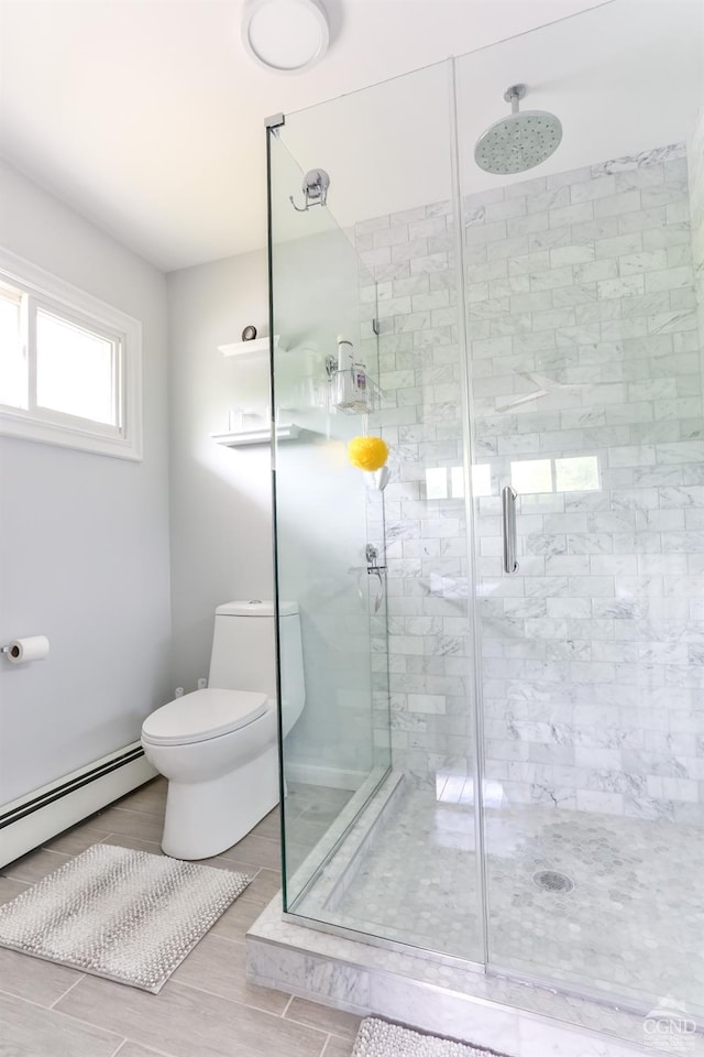 bathroom featuring toilet, baseboard heating, and a shower with shower door