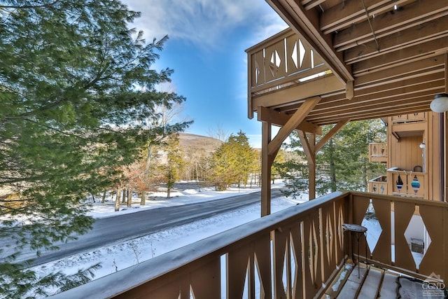 snow covered back of property featuring a mountain view