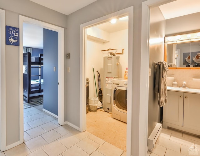 bathroom with baseboard heating, tile patterned flooring, electric water heater, vanity, and washer / dryer