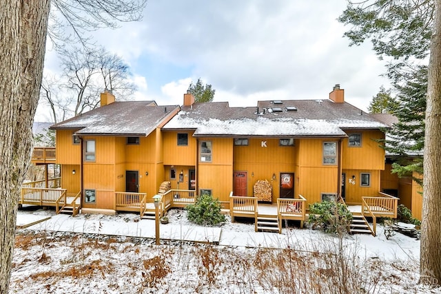 snow covered rear of property featuring a deck