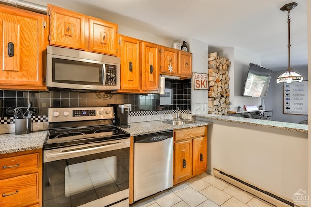 kitchen with sink, hanging light fixtures, baseboard heating, appliances with stainless steel finishes, and light stone countertops