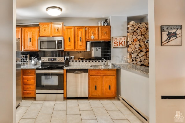 kitchen with appliances with stainless steel finishes, tasteful backsplash, sink, a baseboard heating unit, and light stone countertops