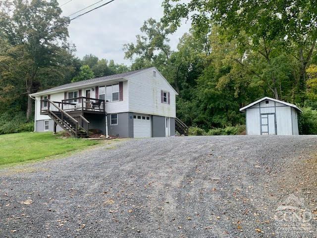 view of front facade with a front yard, a shed, a garage, and a deck