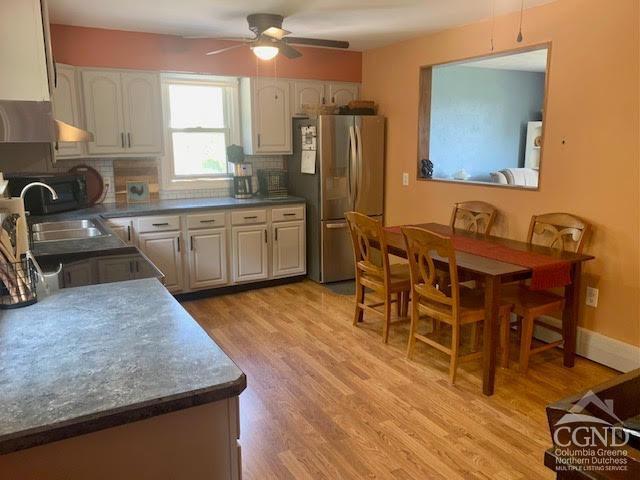 kitchen with sink, light hardwood / wood-style flooring, decorative backsplash, ceiling fan, and stainless steel refrigerator