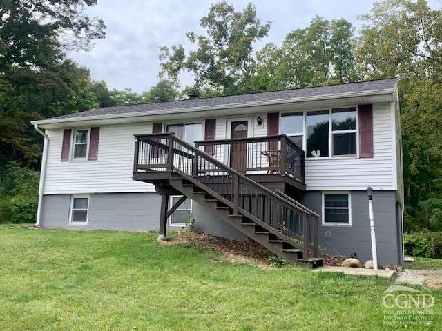 view of front of home with a wooden deck and a front lawn