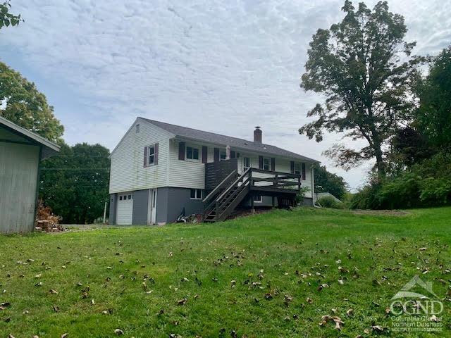 rear view of house with a wooden deck, a yard, and a garage