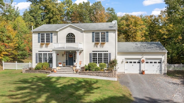 colonial house featuring a balcony, a front lawn, and a garage