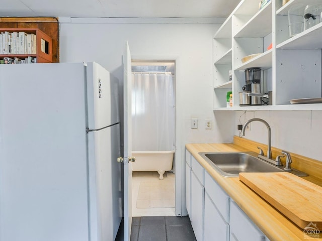 kitchen featuring white fridge, dark tile patterned floors, and sink