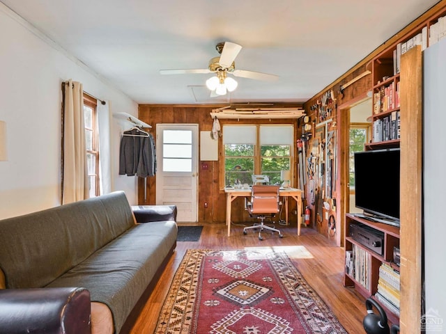 office area featuring wooden walls, crown molding, ceiling fan, and hardwood / wood-style flooring