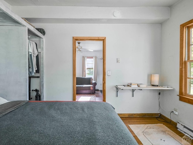 unfurnished bedroom with wood-type flooring and a baseboard heating unit