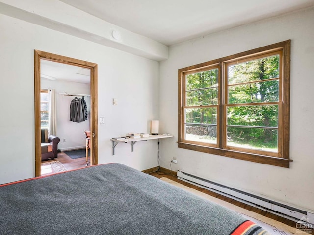 bedroom with hardwood / wood-style flooring, a closet, and a baseboard heating unit