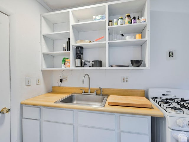 kitchen featuring white cabinets, white gas stove, and sink