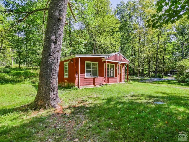 view of outdoor structure with covered porch and a yard