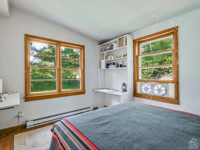 bedroom featuring baseboard heating, wood-type flooring, and lofted ceiling