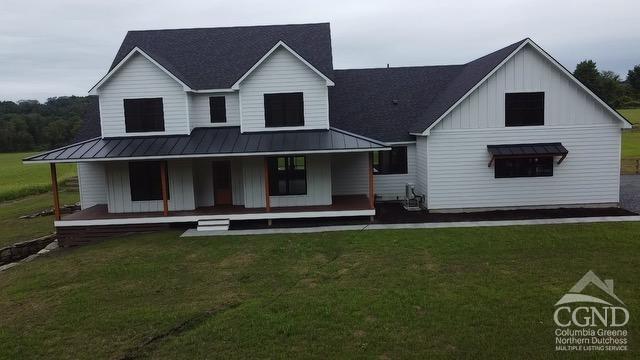 rear view of house with a porch and a yard