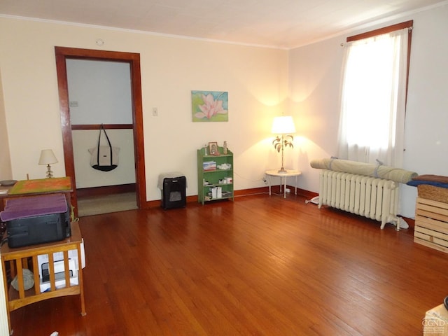 sitting room featuring radiator, ornamental molding, wood finished floors, and baseboards