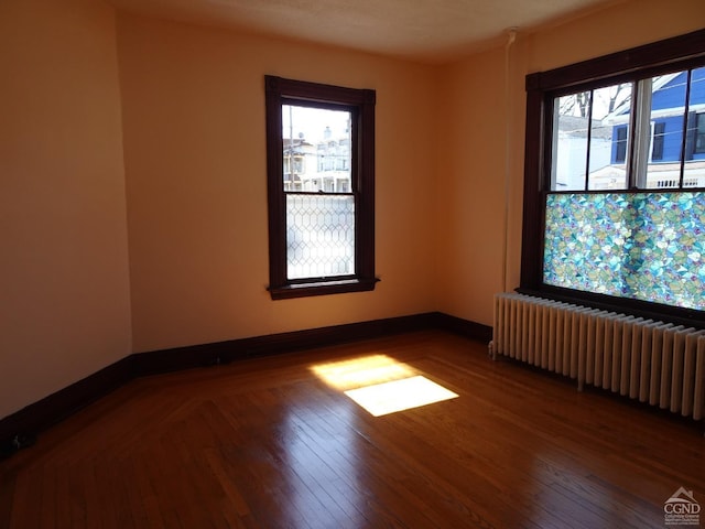 spare room featuring radiator heating unit, wood finished floors, and baseboards