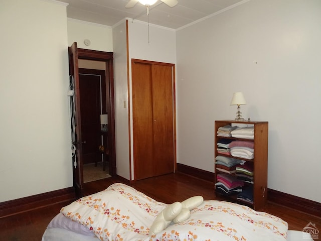 bedroom with crown molding, a closet, wood finished floors, and baseboards
