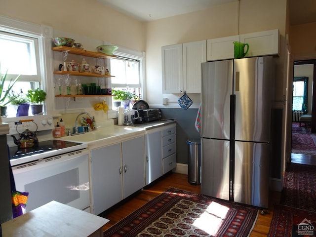 kitchen with a sink, light countertops, freestanding refrigerator, white electric stove, and wood finished floors