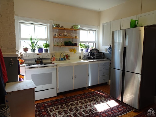 kitchen with electric stove, a sink, light countertops, freestanding refrigerator, and dark wood finished floors