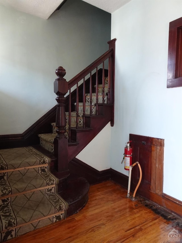 stairway with wood finished floors and baseboards