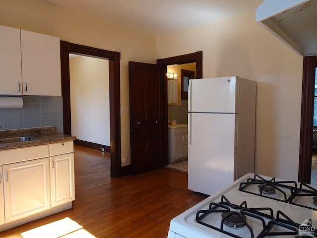 kitchen featuring tasteful backsplash, white appliances, white cabinets, a sink, and dark wood-type flooring