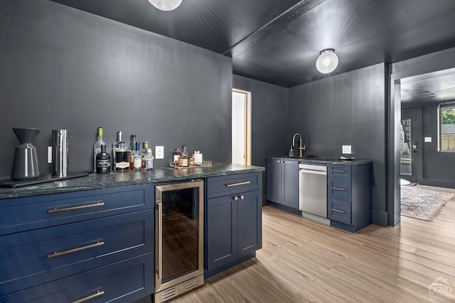 bar with sink, wine cooler, light hardwood / wood-style flooring, stainless steel dishwasher, and blue cabinetry