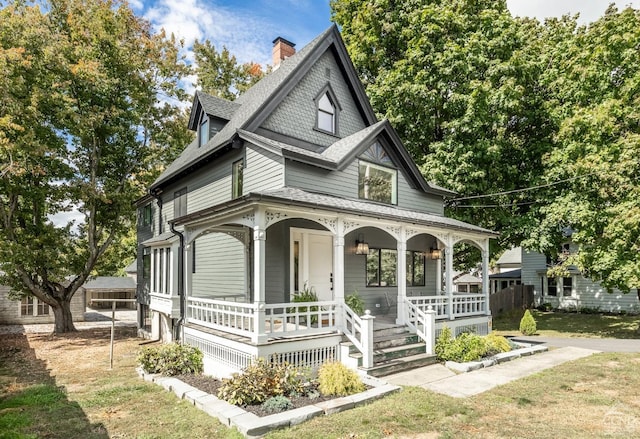 victorian-style house featuring a porch and a front yard