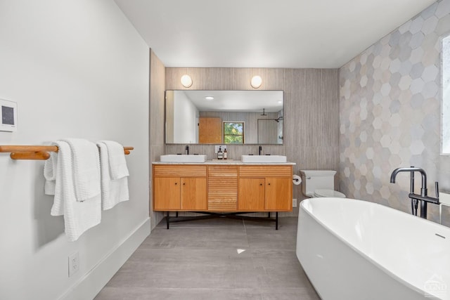 bathroom featuring a tub to relax in, vanity, tile walls, concrete floors, and toilet