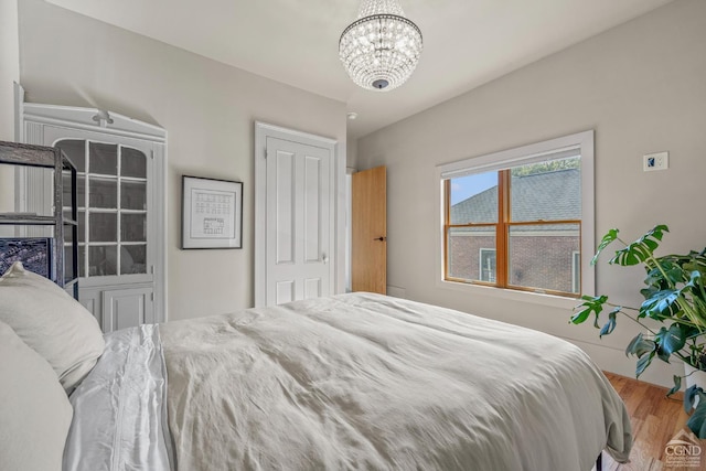 bedroom with wood-type flooring and an inviting chandelier