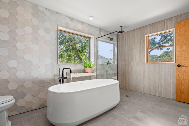 bathroom featuring tile patterned floors, toilet, tile walls, and independent shower and bath