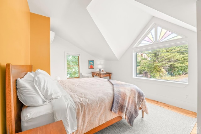 bedroom featuring hardwood / wood-style flooring, multiple windows, and lofted ceiling