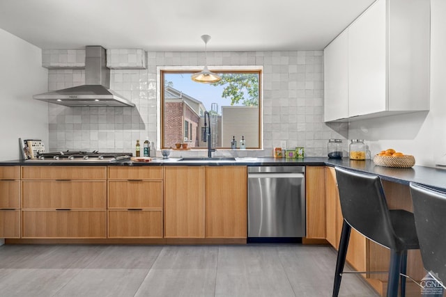 kitchen featuring appliances with stainless steel finishes, backsplash, wall chimney exhaust hood, sink, and white cabinetry