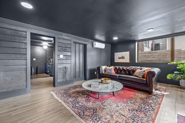 living room featuring a wall mounted air conditioner and light hardwood / wood-style floors