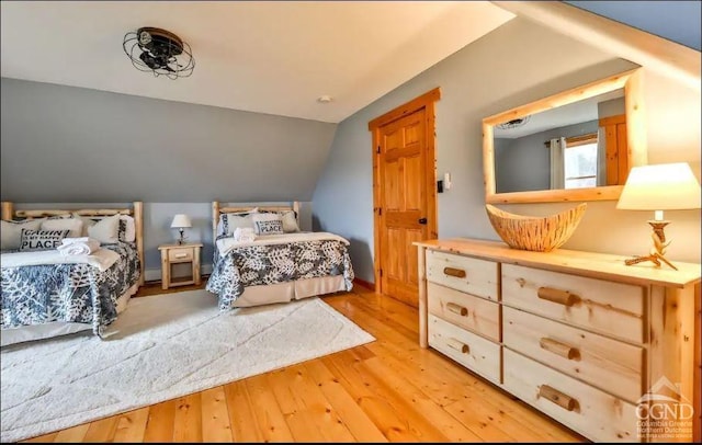 bedroom with light wood-type flooring and lofted ceiling