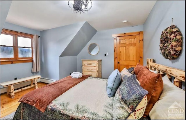 bedroom featuring hardwood / wood-style floors and a baseboard heating unit