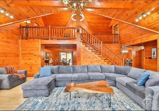 living room featuring wood walls, high vaulted ceiling, and track lighting