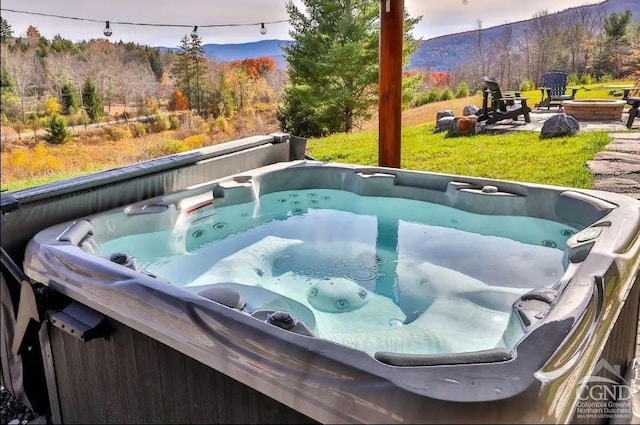 view of swimming pool featuring a mountain view, a yard, and a hot tub