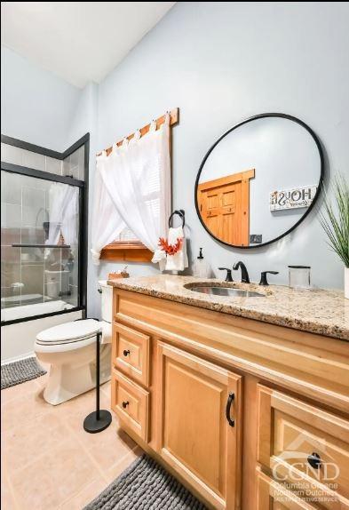 full bathroom with tile patterned flooring, vanity, toilet, and enclosed tub / shower combo