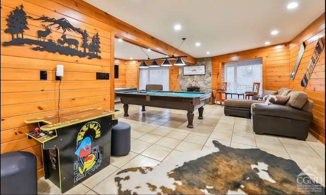 playroom with wood walls, light tile patterned flooring, a stone fireplace, and pool table