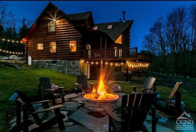 back house at twilight featuring a fire pit, a patio area, and a lawn