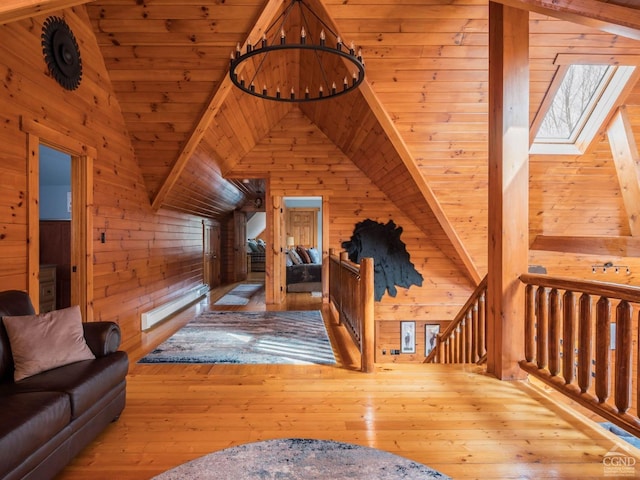 additional living space with wooden ceiling, wood walls, light hardwood / wood-style floors, and a skylight