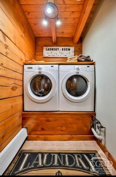 laundry room featuring a baseboard radiator, tile patterned floors, wood walls, washer and clothes dryer, and wood ceiling