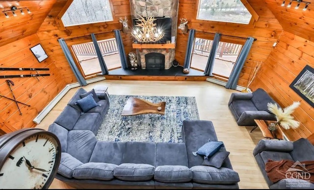 living room with wood walls, rail lighting, vaulted ceiling, a fireplace, and light hardwood / wood-style floors