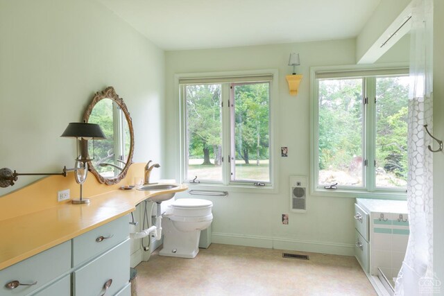 bathroom featuring vanity, heating unit, and toilet