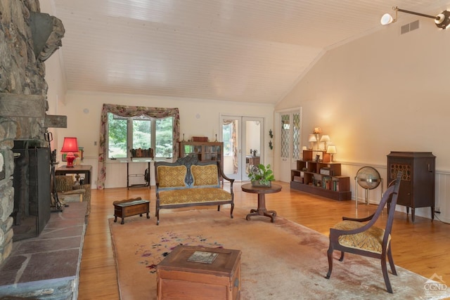 living room featuring french doors, a stone fireplace, lofted ceiling, and wood-type flooring